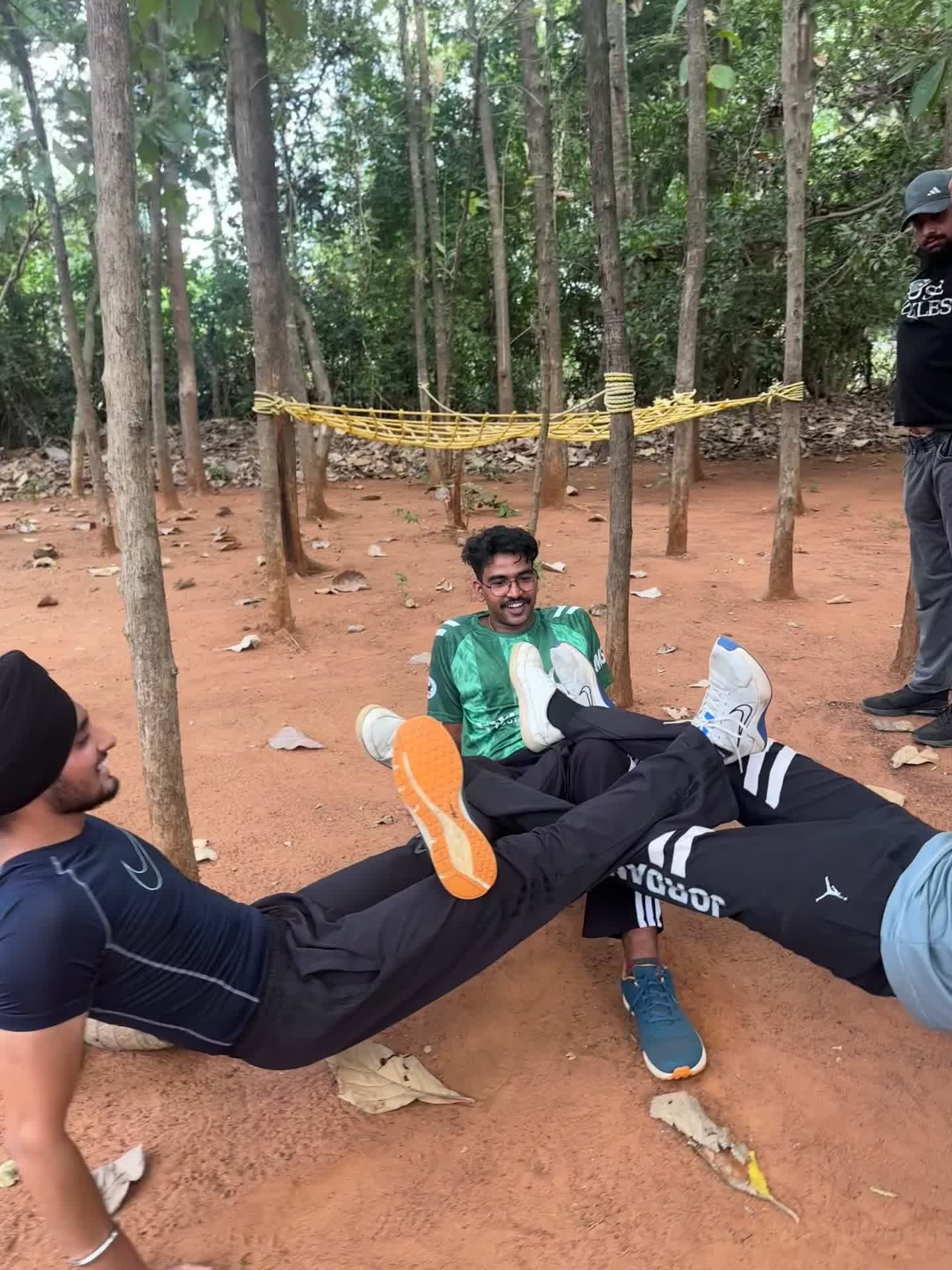 Participants doing a team ground exercise outdoors among trees